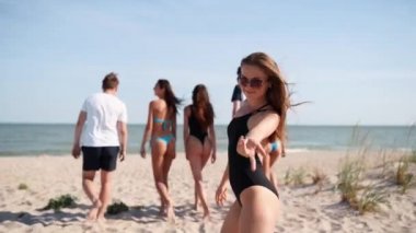 Bikini giymiş güzel bir kadın kameraya bakarken denizde yüzmek istiyor. Sahilde yürüyen mayo giymiş bir kızın arkadan görünüşü, döner ve katılmaya davet eder, takip eder. Arkadaşlar okyanus kıyısına yavaş çekimde giderler..