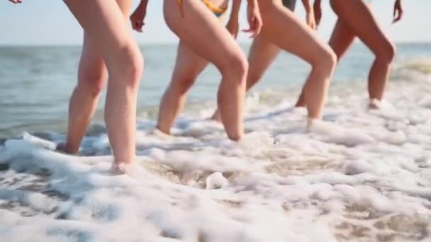 Slim gambe femminili e piedi a piedi che escono dalle onde di acqua di mare sulla spiaggia di sabbia. Le belle donne si spostano sul lungomare. Schizzi d'acqua e schiuma in 120 fps al rallentatore. Ragazze dopo il bagno nell'oceano andare a riva . — Video Stock