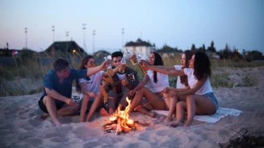 Arkadaşlar şenlik ateşinin etrafında oturur, bira şişelerini kızartır gitar çalar ve kumsalda sosis kızartırlar. Genç bir grup erkek ve kadın birlikte içki içiyorlar. Alacakaranlıkta gitar çalan adam..