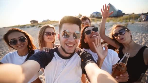 Vista Pov de jovens amigos tomando selfie se divertindo com bebidas na praia do mar ao pôr do sol. Chamada de vídeo on-line: homem olhando para câmera de smartphone na ilha tropical, mulheres brindando limonada, acenando as mãos. — Vídeo de Stock