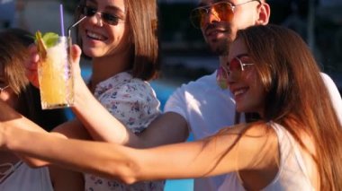 Güler yüzlü arkadaşlar havuz başı partisinde akıllı telefonlarıyla selfie çekiyorlar. Güneşli yaz gününde havuz başında taze renkli kokteyller hazırlıyorlar. Tropikal tatilde lüks villada fotoğraf çeken bir kadın..