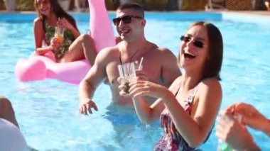 Arkadaşların havuzda kokteyllerle parti veriyor. Güneşli bir günde mayo giyen, dans eden, kaynaşan, şişme flamingo, kuğu ve şilte kullanan mutlu gençler..