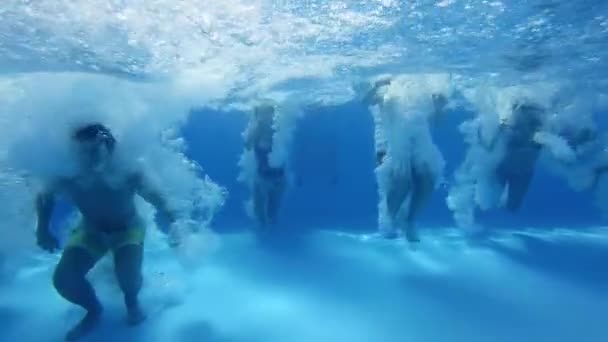 Imágenes submarinas de amigos felices saltando y salpicando en la piscina. Los jóvenes en trajes de baño que tienen fiesta de buceo bajo el agua en la villa privada de vacaciones. Chicas calientes saltar al agua en el día de verano. — Vídeo de stock