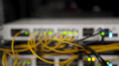 Veri merkezi sunucu odasının optik sunucusu ve yönlendiricisi. Ağ ekipmanları ışıklarla yanıp sönüyor. Optik fiber kablolar bağlantı noktalarına bağlı. Yüksek hızlı İnternet.