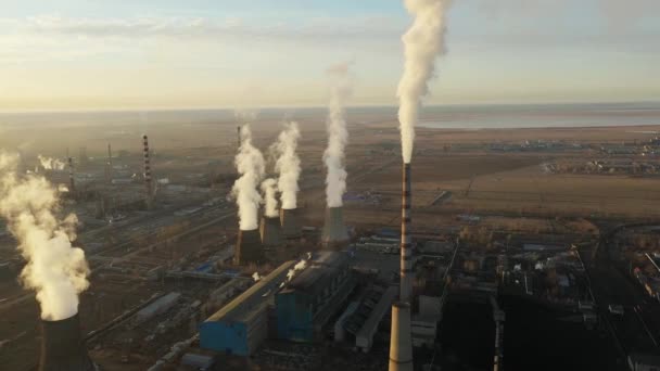 Vista aérea da central térmica. O drone voa sobre os tubos de fumaça da chaminé e as torres de refrigeração da área industrial no por do sol. Estação térmica de geração de eletricidade de cima esgota as emissões atmosféricas. — Vídeo de Stock