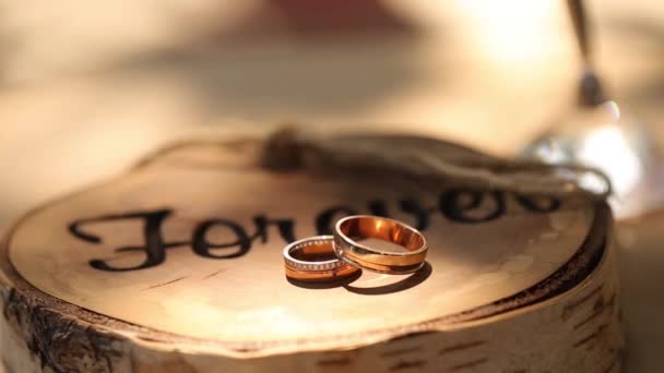 Svatební prsteny leží na pařezu v rustikálním stylu stojan s nápisem "navždy" na obřadu pro ženicha a nevěstu — Stock video