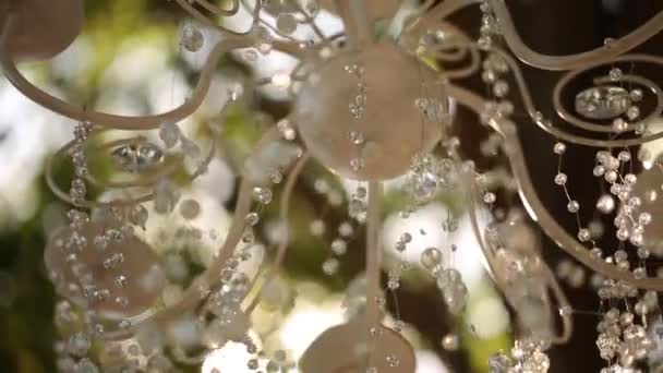 Kryształowy żyrandol z kwiatami i girlandami na ceremonii ślubnej. Wystrój wakacyjny w stylu rustykalnym. — Wideo stockowe