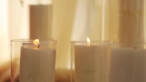 Queimar velas em frascos de vidro fica no chão do salão de celebraiotion, coberto com tecido branco e cortinas bege no fundo. Noite romântica. Decoração de casamento — Vídeo de Stock