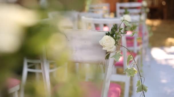 Erstaunlich rustikale Dekoration der Hochzeitszeremonie mit Heu, Stühlen, floristischen Kompositionen und Hochzeitskleid, das an einem Baum im Hintergrund hängt. Sommerland-Hochzeitskonzept — Stockvideo