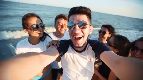 Pov view of young friends taking selfie having fun with drinks on sea beach on sunset. Online videosamtal: man tittar på smartphone kamera på tropiska ön, kvinnor rostning lemonad, viftande händer. — Stockvideo