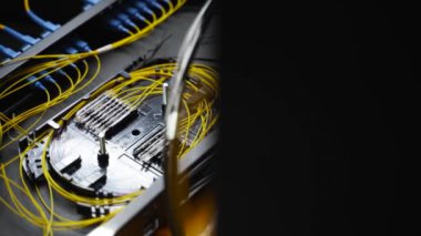 İşçi, bağlantı kutusunda optik hat internet kablosu bağlıyor. Servis elemanı optik fiber lehim yapıyor. Optik fiber ve yönlendirici kablolarıyla sunucu odasında çalışan internet servis sağlayıcısı mühendisi..
