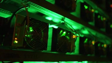 Bitcoin madencileri büyük çiftlikte. Kürsüdeki ASIC madencilik ekipmanları çelik konteynırdaki kripto para birimini rafa kaldırıyor. Engelleme teknolojisi. Güç kaynağı vantilatörleri ve ızgaralar. Sunucu odası ışıkları.