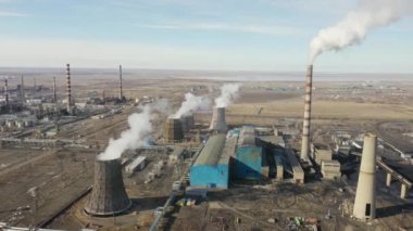 Termik santralin hava görüntüsü. İnsansız hava aracı günbatımında baca dumanı borularının ve sanayi bölgesinin soğutma kulelerinin üzerinden uçuyor. Yukarıdan gelen termal elektrik üretim istasyonu hava emisyonlarını tüketiyor.