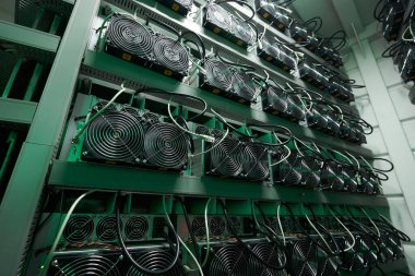 Bitcoin madencileri büyük çiftlikte. Kürsüdeki ASIC madencilik ekipmanları çelik konteynırdaki kripto para birimini rafa kaldırıyor. Entegre devre veri tabanında engelleme zinciri uygulaması. Sunucu odası ışıkları.