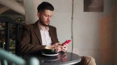 Kafede otururken akıllı telefon kullanan klas bir genç. Tabuttaki sosyal ağ uygulamasına bakan bir adam. Ofis çalışanı molada bir fincan kahveyle dinleniyor. İç mekan.