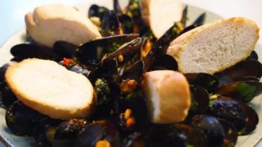 Lüks restoran ziyaretçileri için büyük bir tabakta lezzetli taze midyeler pişiriliyor. Geleneksel meditasyon tabağı tepside dönüyor. Yavaş çekim.