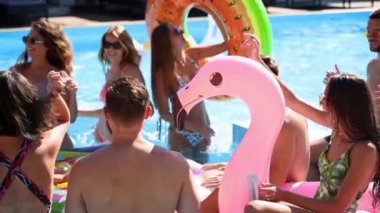 Arkadaşlar özel bir villada yüzme havuzunda parti yaparlar. Güneşli bir günde mayo giyen, dans eden, şamandıralarla takılan ve lüks bir tatil köyünde şişme yatak giyen mutlu gençler. Yavaş çekim.