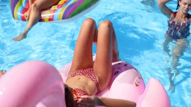 Fille chaude en bikini relaxant sur flamant rose gonflable. Amis se rafraîchissant sur les floaties, matelas dans la piscine de villa privée. Les jeunes se détendent à la fête dans un complexe de luxe par une journée ensoleillée. Mouvement lent — Video