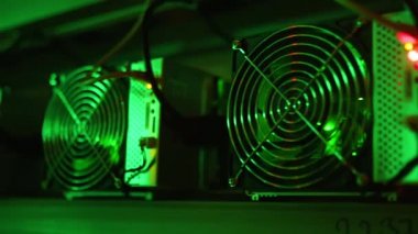 Bitcoin madencileri büyük çiftlikte. Kürsüdeki ASIC madencilik ekipmanları çelik konteynırdaki kripto para birimini rafa kaldırıyor. Engelleme teknolojisi. Güç kaynağı vantilatörleri ve ızgaralar. Sunucu odası ışıkları.
