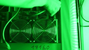 Kripto para çiftliğindeki Bitcoin madencilik ekipman servisi. Teknisyen ASIC madencilerinin veri tabanı odasındaki raflarına güç kablosu bağlayıcı yerleştiriyor. Engelleme zinciri donanım donanımı kurulum görüntüleri.