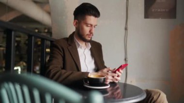 Kafede otururken akıllı telefon kullanan klas bir genç. Tabuttaki sosyal ağ uygulamasına bakan bir adam. Ofis çalışanı molada bir fincan kahveyle dinleniyor. İç mekan.
