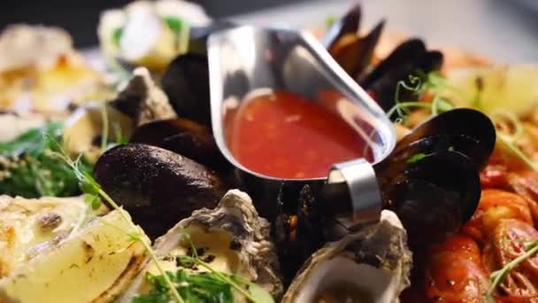 Ensemble de fruits de mer cuisinés, crevettes, crevettes royales, moules, huîtres et calmars sont servis dans une grande assiette de salver pour les visiteurs du restaurant de luxe. Plat méditarien traditionnel tournant sur un plateau. — Video