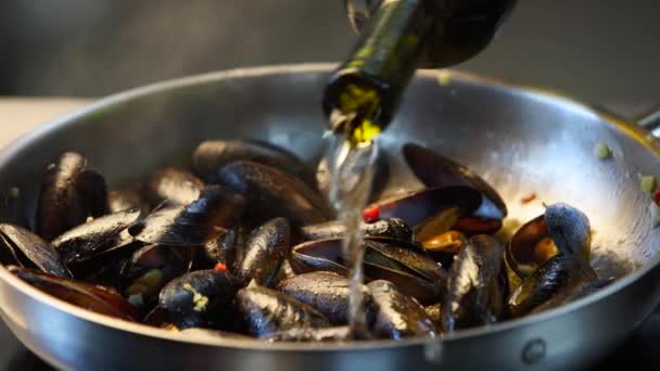 Cuisson de délicieuses moules fraîches sur une poêle chaude dans un restaurant de luxe. Verser le plat avec du vin blanc sec. Cuisine méditerranéenne traditionnelle. Scène de ralenti. — Video