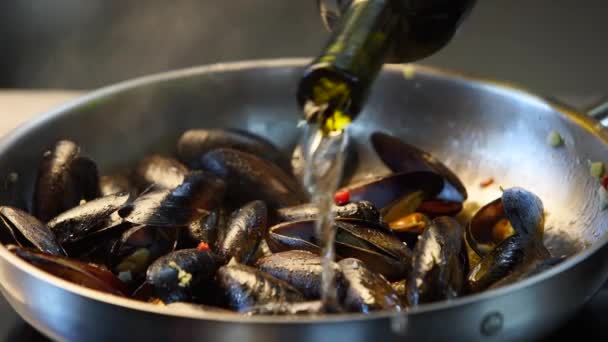 Cocinar deliciosos mejillones frescos en una sartén caliente en un restaurante de lujo. Verter el plato con vino blanco seco. Cocina mediterránea tradicional. Escena de cámara lenta. — Vídeos de Stock