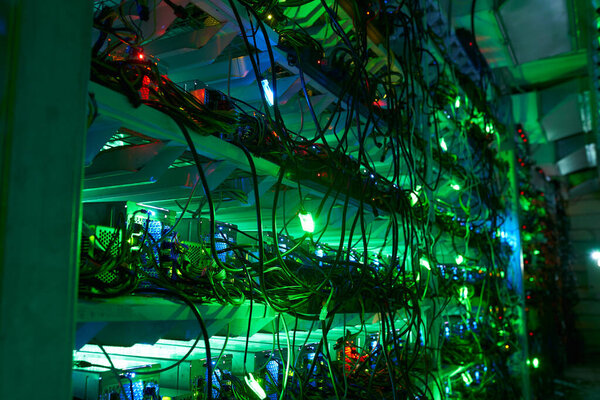 Bitcoin miners in large farm. ASIC mining equipment on stand racks mine cryptocurrency in steel container. Blockchain techology application specific integrated circuit datacenter. Server room lights.