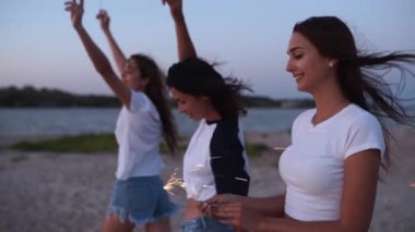 Kadın arkadaşlar yürüyor, dans ediyor, ellerinde maytaplarla sahildeki partide eğleniyorlar. Genç kızlar plajda havai fişeklerle, bengal ışıklarıyla parti yapıyorlar. Ağır çekimde kızlar, sabit kameralı çekim.