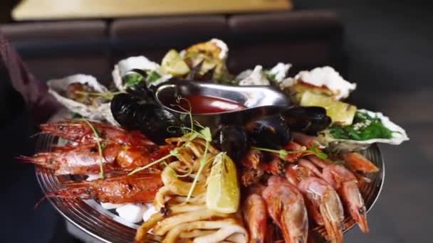 Los camareros llevan un conjunto de mariscos mixtos, camarones langosta, langostinos, mejillones, ostras y calamares servidos en un gran plato salver para los visitantes de restaurantes de lujo. Garcon trae plato meditario tradicional. — Vídeos de Stock