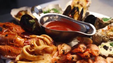 Lüks restoran ziyaretçileri için büyük bir tabakta pişirilmiş deniz ürünleri, ıstakoz karidesi, kral karidesi, midye, istiridye ve mürekkep balığı servis edilir. Bir tepside dönen geleneksel meditaryen yemek.