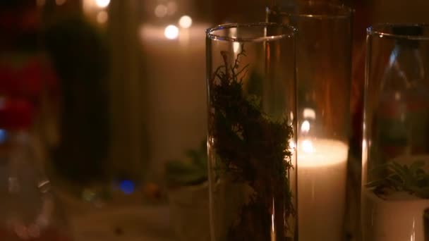 Svatební hostina venku v lese. Jídelní stůl zdobený ve stylu boho s hořícími svíčkami, bílou látkou, květinami, servírovaný s talíři, stolním nádobím, nápojem, nápojem a nápojem v noci. — Stock video