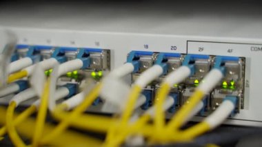 Veri merkezi sunucu odasının optik sunucusu ve yönlendiricisi. Ağ ekipmanları ışıklarla yanıp sönüyor. Optik fiber kablolar bağlantı noktalarına bağlı. Yüksek hızlı İnternet.