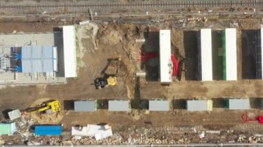 Güçlü sarı kazıcı havası kovayla çukur kazıyor. Yeraltı güç kablolarını kırmızı esnek çift katmanlı borularla döşemek. Construstion sitesine elektrik hatları kurulumu.