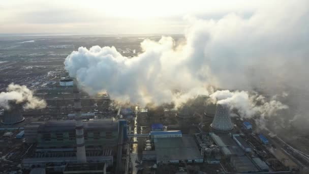 Luftaufnahme des thermischen Kraftwerks. Drohne fliegt bei Sonnenuntergang über Rauchrohre und Kühltürme im Industriegebiet. Thermische Stromerzeugungsanlage von oben führt zu Luftverschmutzung. — Stockvideo