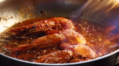 Lüks bir restoranda sıcak alevlerle taze kırmızı kral karidesleri ızgara yapmak. Şef kraliyet karideslerini ateşle kızartıyor. Makro deniz ürünleri hazırlığı. Gastronomi deniz mahsulleri barbeküsüne yakından bakın..
