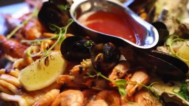 Lüks restoran ziyaretçileri için büyük bir tabakta pişirilmiş deniz ürünleri seti, ıstakoz karidesi, kral karidesi, midye, istiridye ve mürekkep balığı servis edilir. Bir tepside dönen geleneksel meditaryen yemek.