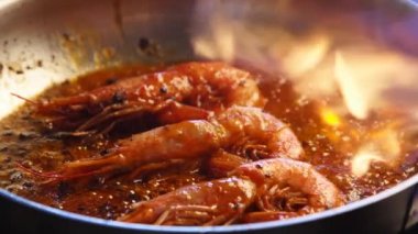 Lüks bir restoranda sıcak alevlerle taze kırmızı kral karidesleri ızgara yapmak. Şef kraliyet karideslerini ateşle kızartıyor. Makro deniz ürünleri hazırlığı. Gastronomi deniz mahsulleri barbeküsüne yakından bakın..