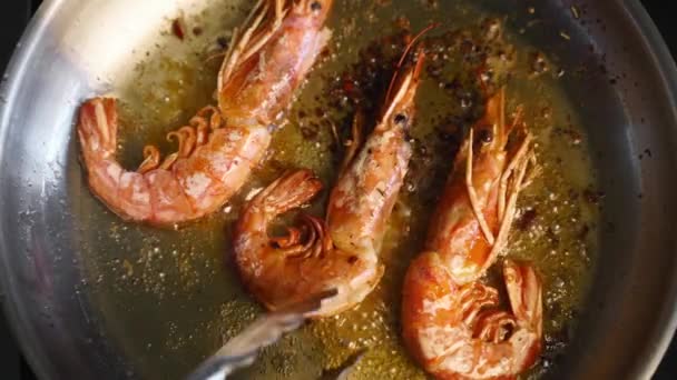 Cook convierte los camarones con fórceps en una parrilla. Primer plano de langostinos fritos en una sartén. Chef freír camarones reales en una sartén caliente. Preparación de alimentos de mar macro. — Vídeo de stock