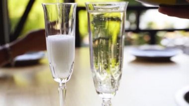 Garson bardaklara şampanya dolduruyor. Garson köpüklü şarabı bardağa doldurur. Barmen lüks restoran ziyaretçileri için içki dolduruyor..