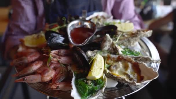 服务员们带着混合海鲜套餐、龙虾、国王虾、贻贝、牡蛎和杂烩，放在豪华餐馆游客的大盘子里。Garcon带来了传统的杂烩菜. — 图库视频影像