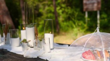 Meyve dilimleri sineklerin yemek çadırının altında ormanın dışındaki düğün yemeği ziyafetinde servis edilir. Yemek masası, mum, beyaz bez ve sofra takımı ile süslenmiş..