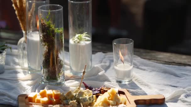 Festa de casamento banquete ao ar livre na floresta. Mesa de jantar decorada em estilo boho com velas, pano branco, flores, servido com pratos, utensílios de mesa, pratos, refeições, utensílios de stemware e bebidas. Férias catering. — Vídeo de Stock