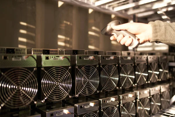 Controller in Uniform scannt ASIC Bitcoin Miners mit Barcode-Scanner im Lager. Lagerist bei der Arbeit im Lagerraum. Arbeiter scannt Barcodes von Netzteilen in Service-Reparaturzentrum. — Stockfoto