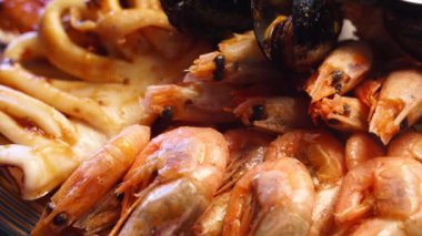 Lüks restoran ziyaretçileri için büyük bir tabakta pişirilmiş deniz ürünleri, ıstakoz karidesi, kral karidesi, midye, istiridye ve mürekkep balığı servis edilir. Bir tepside dönen geleneksel meditaryen yemek.