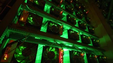Bitcoin madencileri büyük çiftlikte. Kürsüdeki ASIC madencilik ekipmanları çelik konteynırdaki kripto para birimini rafa kaldırıyor. Entegre devre veri tabanında engelleme zinciri uygulaması. Sunucu odası ışıkları.