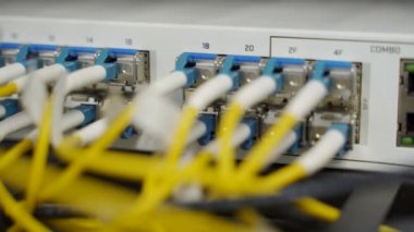 Veri merkezi sunucu odasının optik sunucusu ve yönlendiricisi. Ağ ekipmanları ışıklarla yanıp sönüyor. Optik fiber kablolar bağlantı noktalarına bağlı. Yüksek hızlı İnternet.