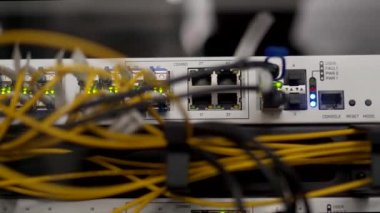 Veri merkezi sunucu odasının optik sunucusu ve yönlendiricisi. Ağ ekipmanları ışıklarla yanıp sönüyor. Optik fiber kablolar bağlantı noktalarına bağlı. Yüksek hızlı İnternet.