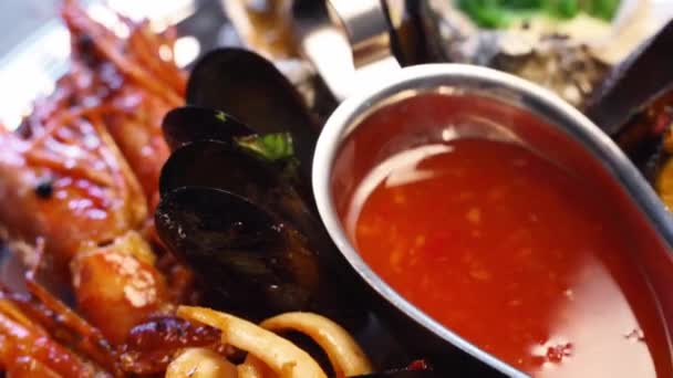 Des fruits de mer cuisinés, des crevettes, des crevettes royales, des moules, des huîtres et des calmars sont servis dans une grande assiette de salver pour les visiteurs du restaurant de luxe. Plat méditarien traditionnel tournant sur un plateau. — Video